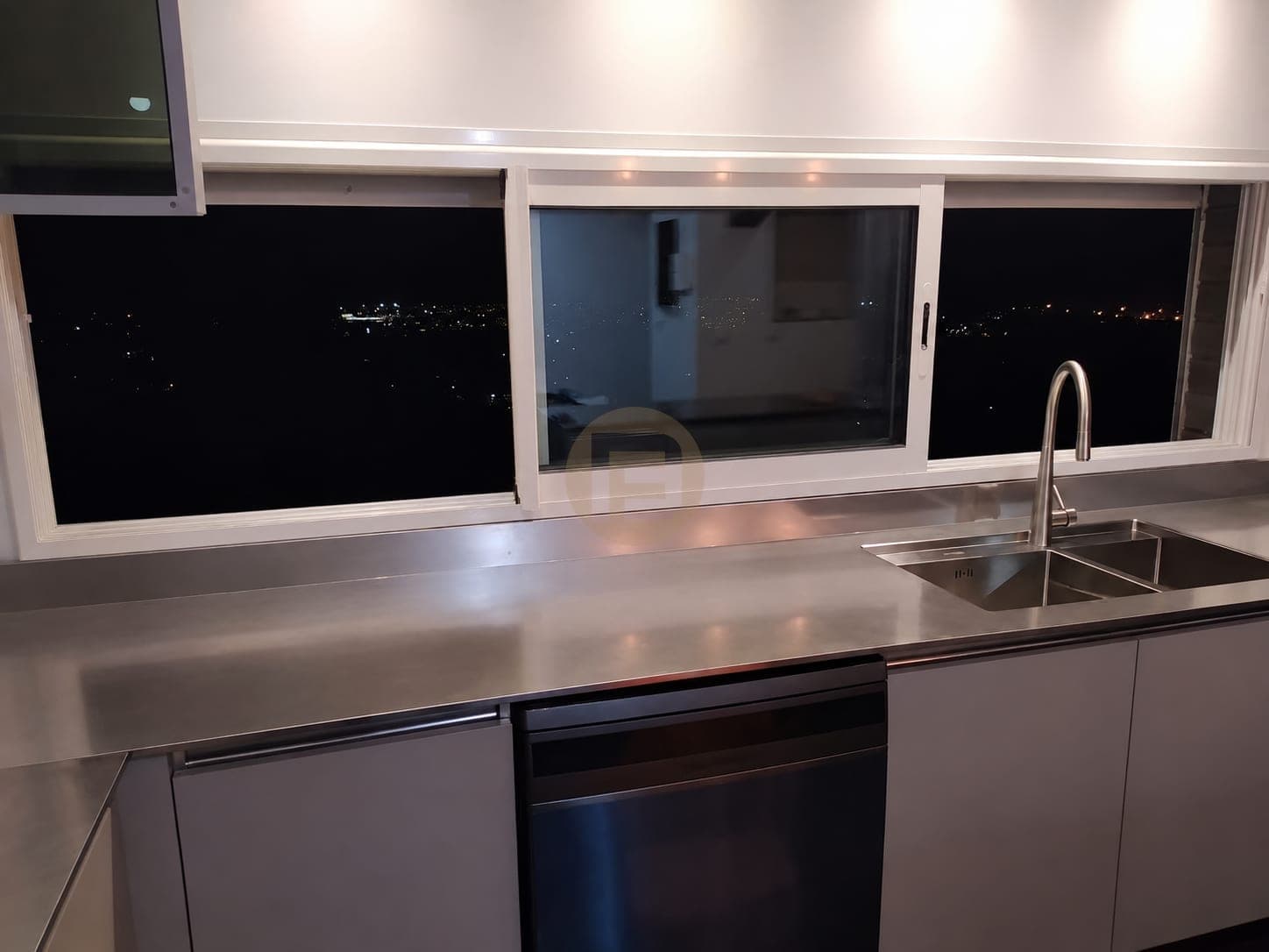 Stainless steel worktop run beside the blue island at night