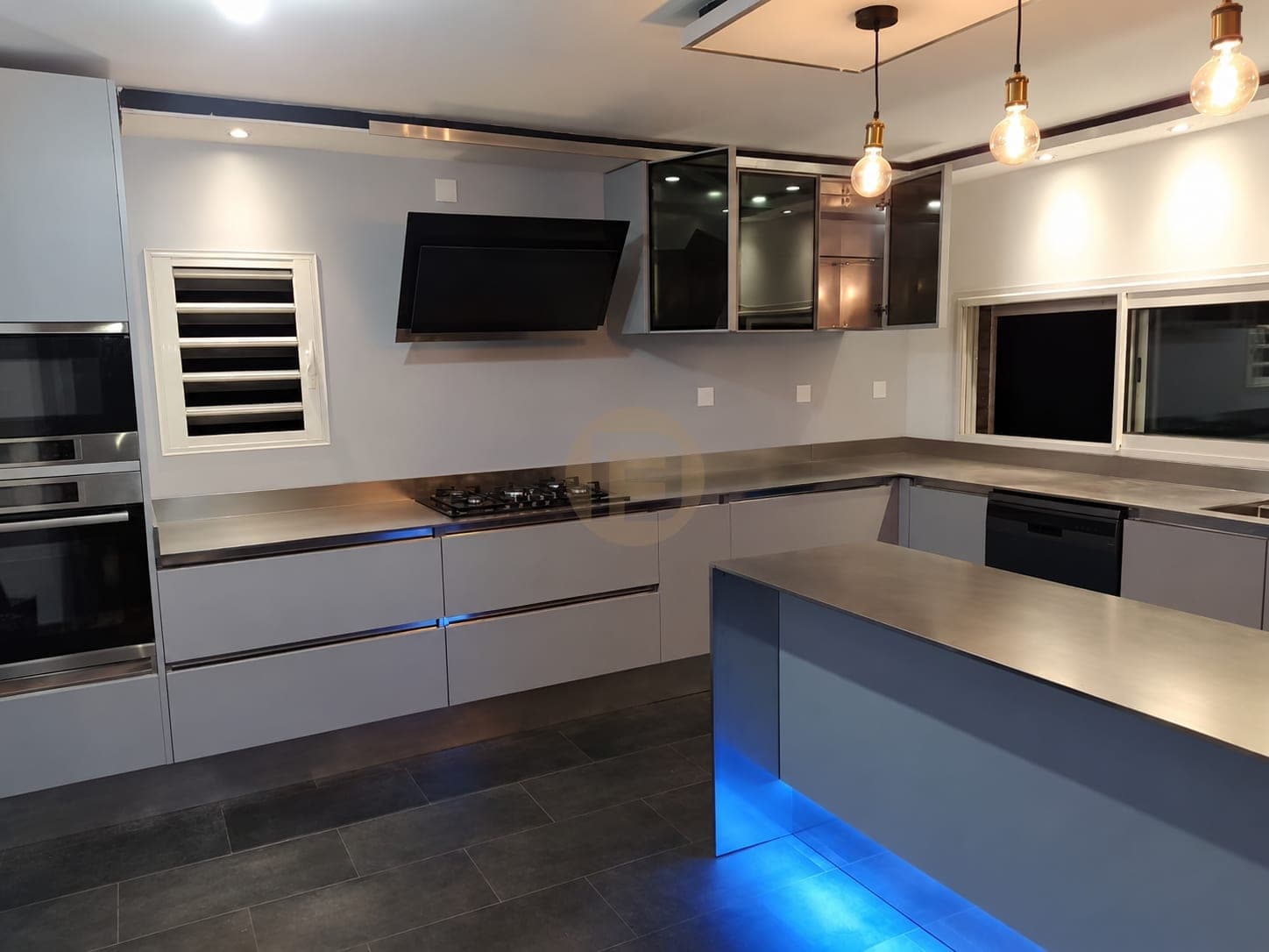 Blue kitchen island with a lit base and stainless steel perimeter worktop