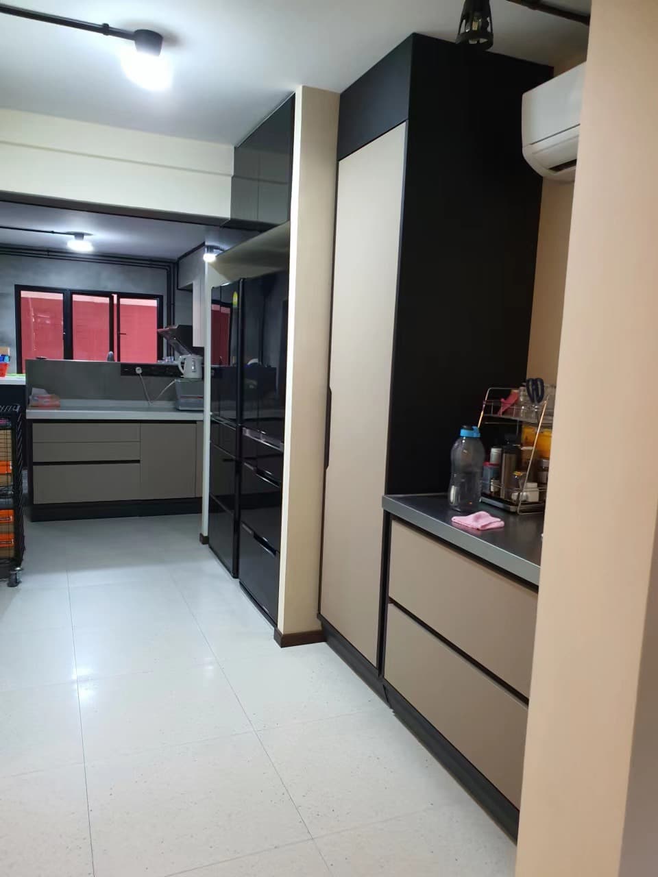 View down the kitchen toward dark tall storage and the appliance area