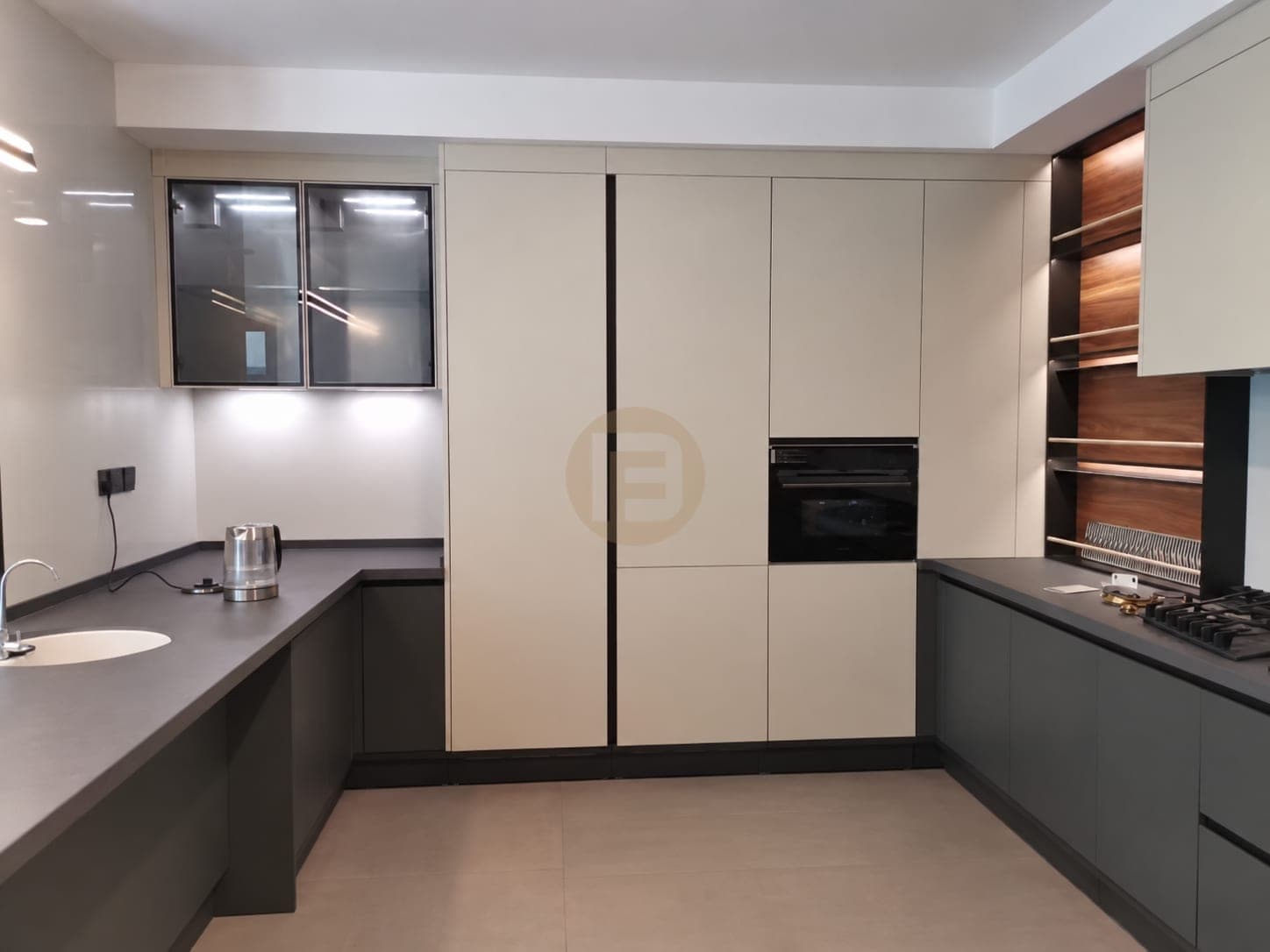 Cream tall-cabinet wall with a built-in oven between charcoal worktop runs