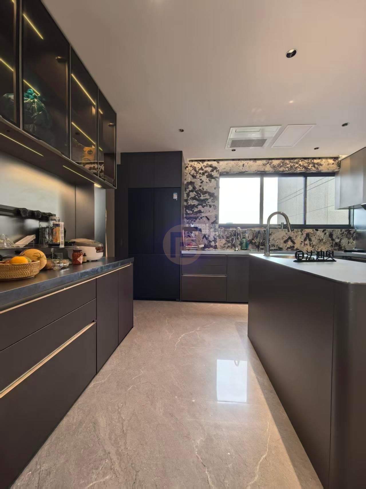 Pared de cocina oscura con muebles altos de cristal, iluminación lineal y encimera