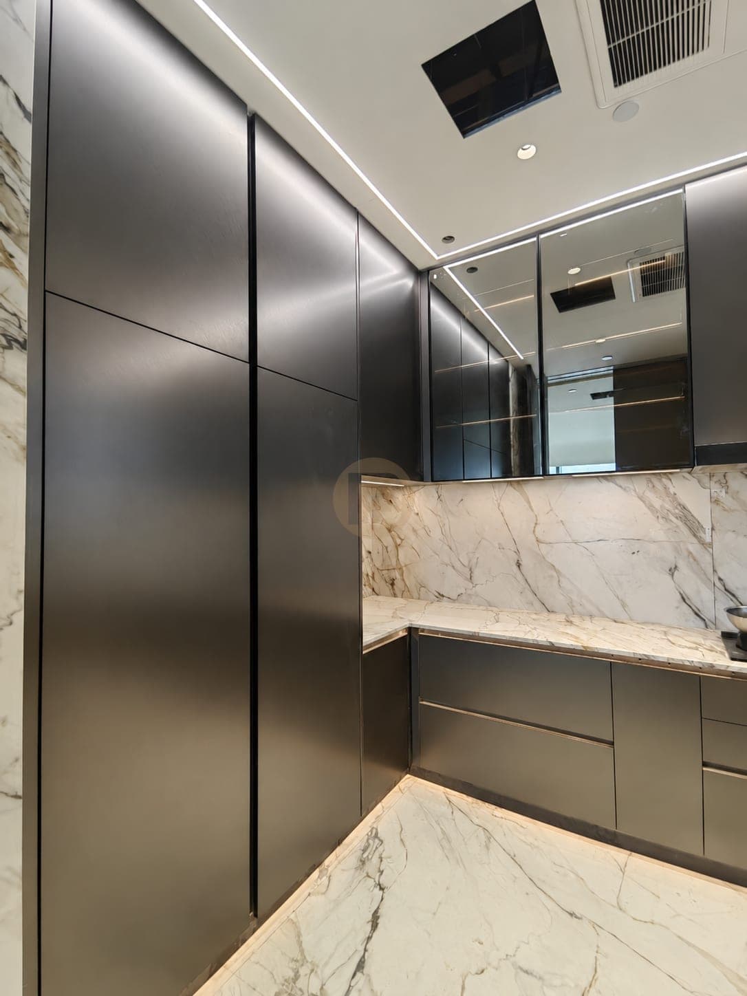 Dark metallic tall cabinets beside glass wall cabinets and a marble-look backsplash