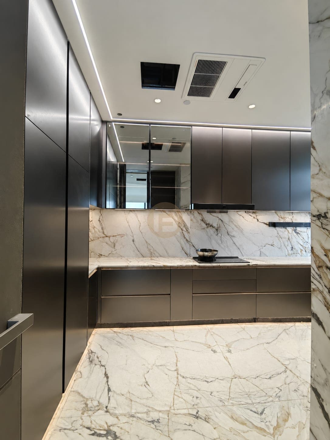 Kitchen view of dark metallic cabinetry, glass wall units and a marble-look floor