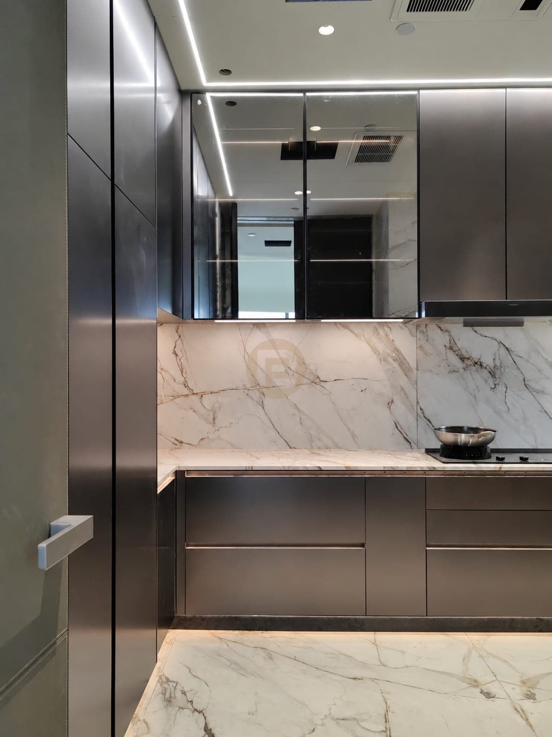 Dark metallic base drawers and glass wall cabinets above a marble-look backsplash