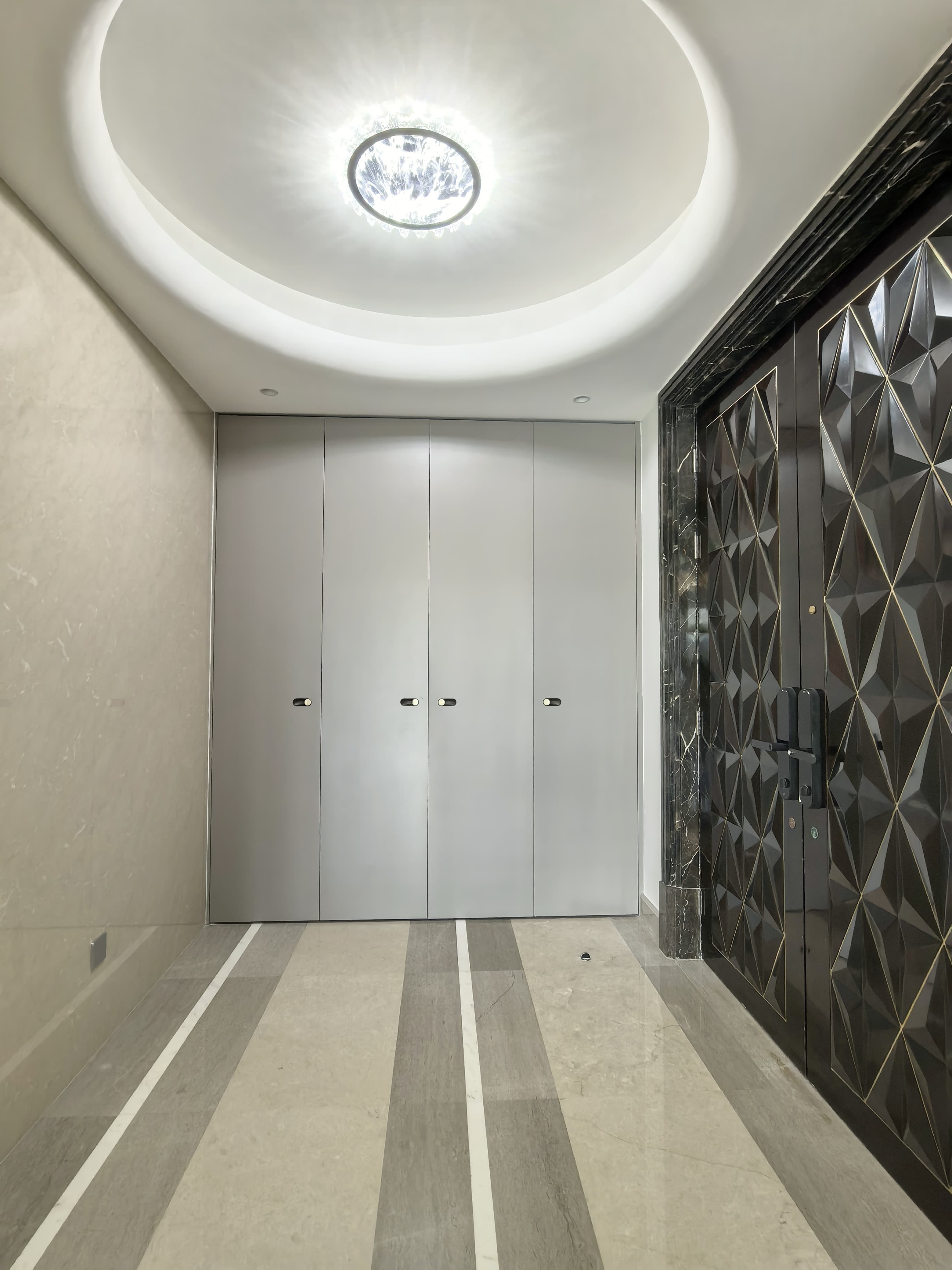 Full-height grey entry storage beside a dark patterned entrance door