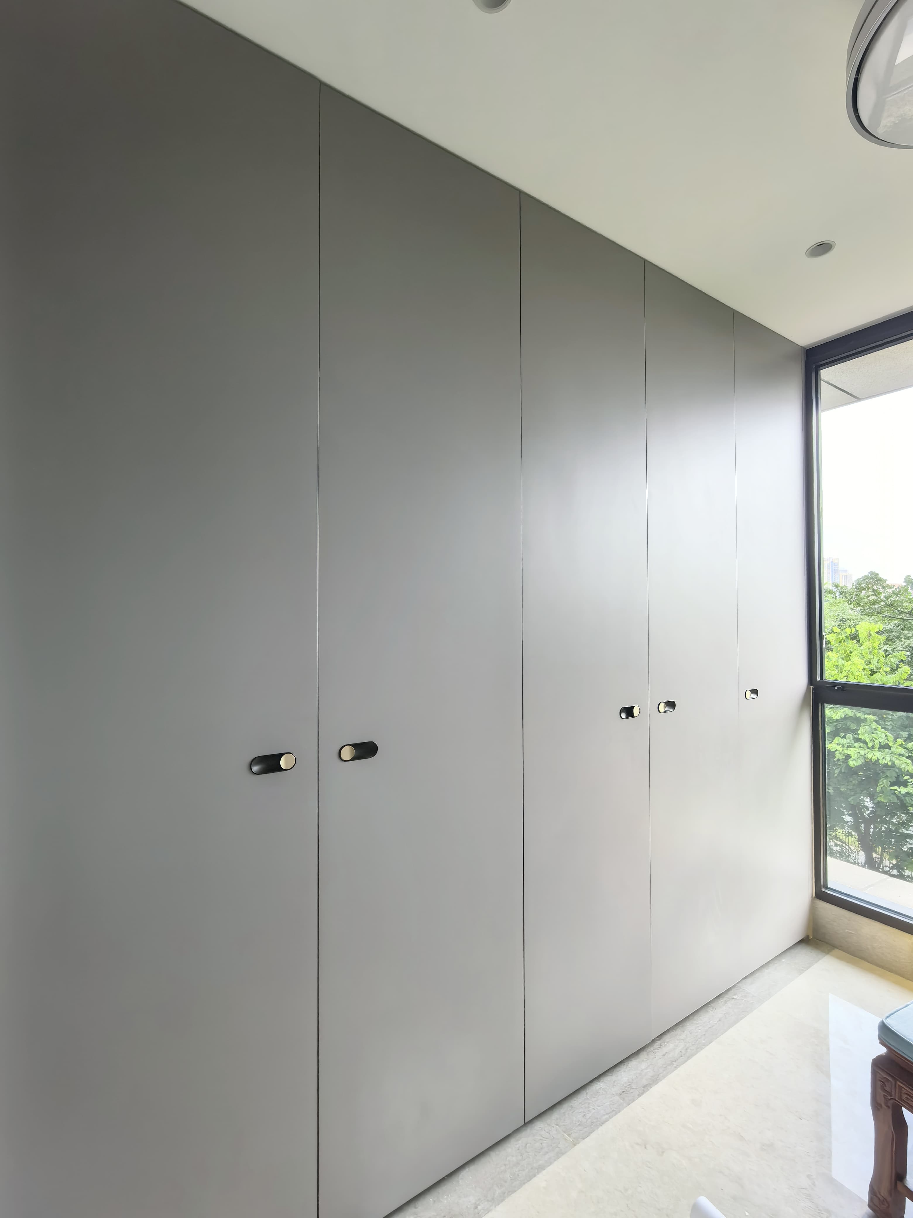 Plain grey wardrobe wall beside a full-height window