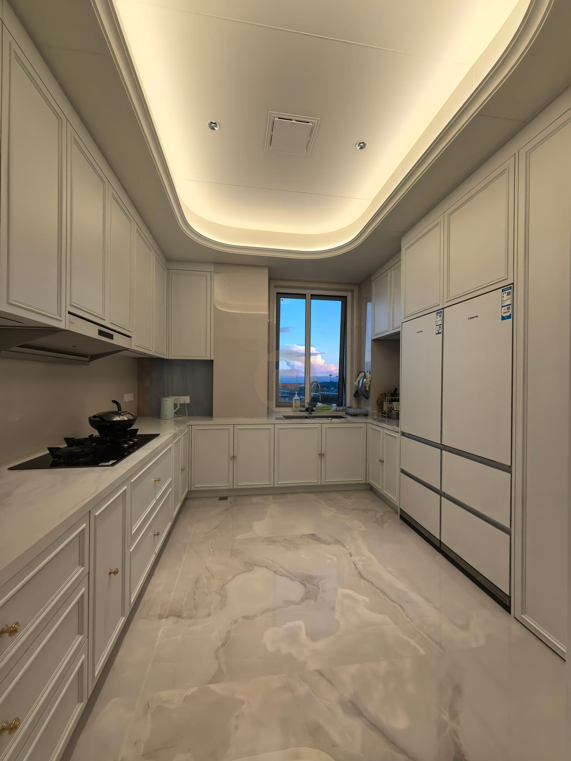 Cocina blanca con frentes de marco decorativo, tiradores pequeños de tono dorado y encimera