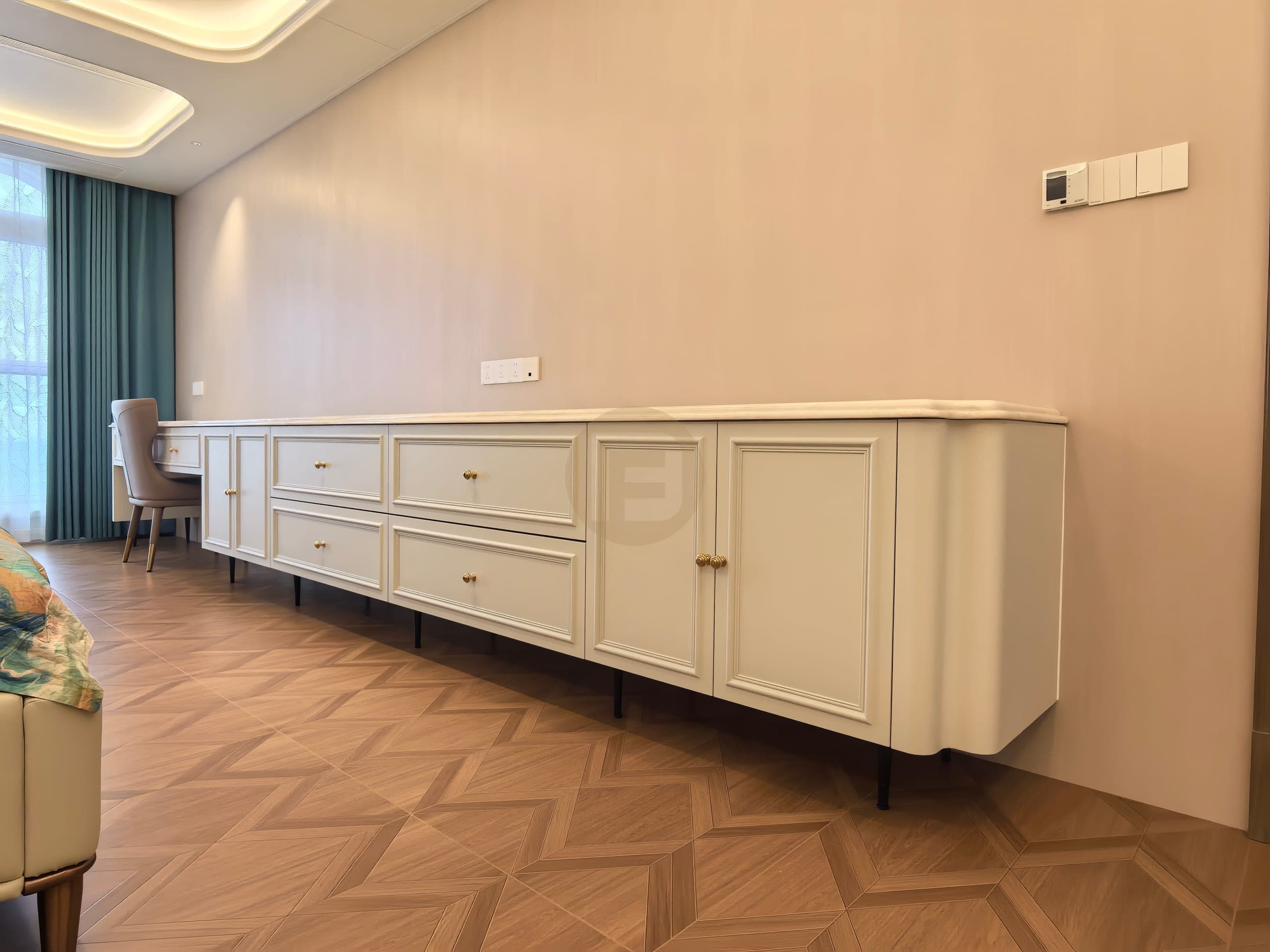 Mueble bajo blanco y largo con puertas enmarcadas, cajones, extremo redondeado y espacio libre para las piernas