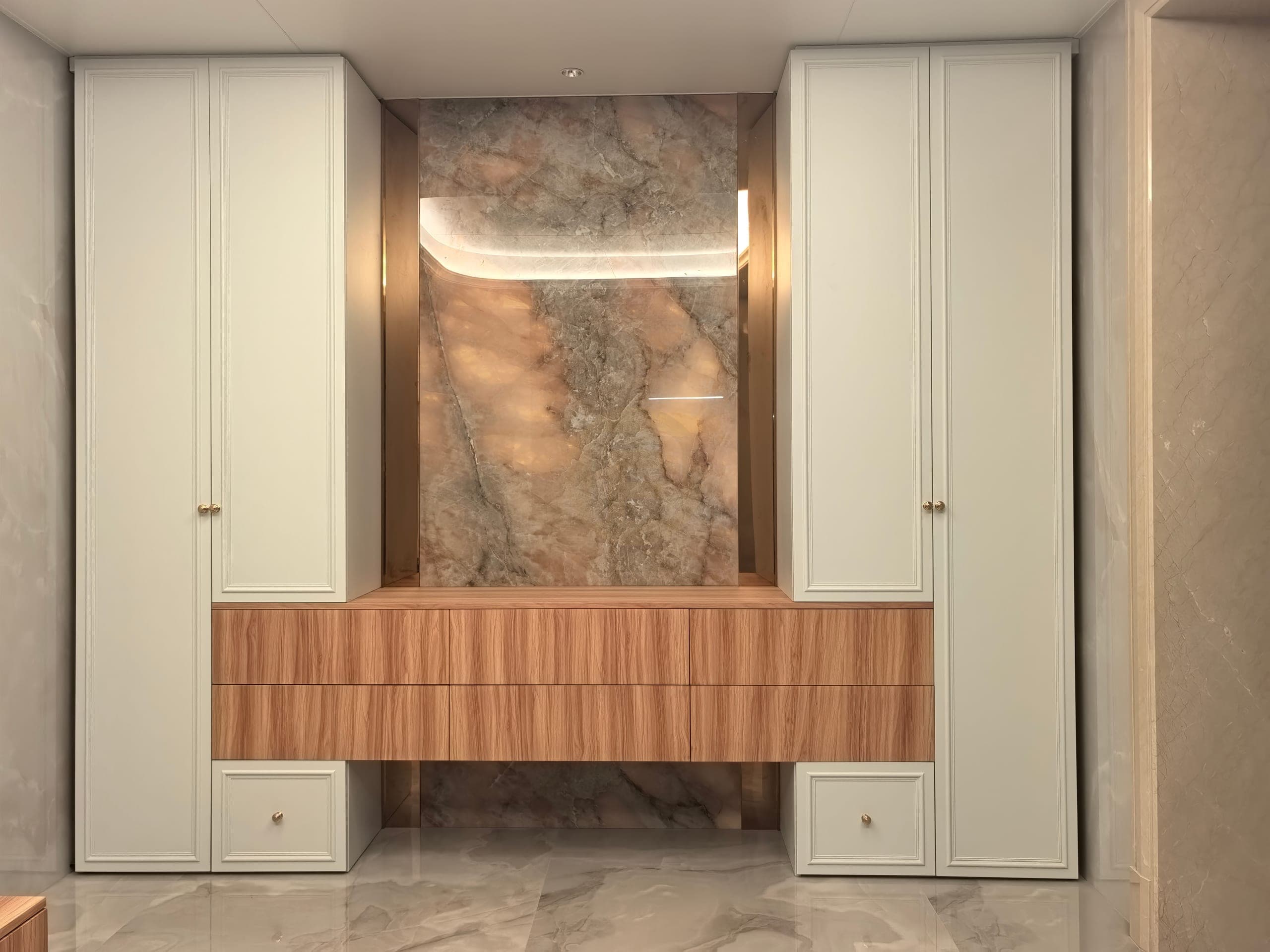 Armarios altos blancos simétricos y cajones de aspecto madera alrededor de un hueco central texturizado