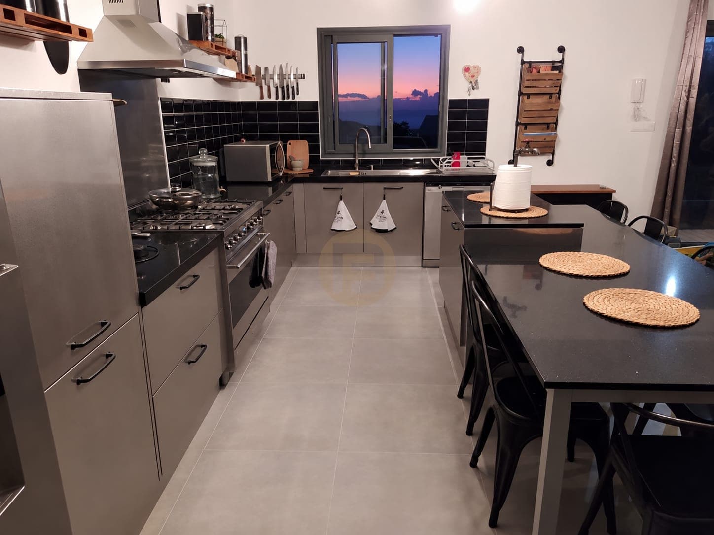 Stainless cabinet run and range cooker leading to a window at dusk
