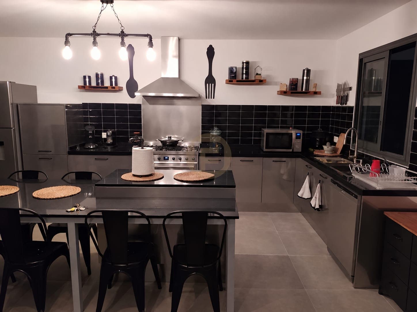 Front view of the stainless kitchen, range cooker and island table under pipe pendants