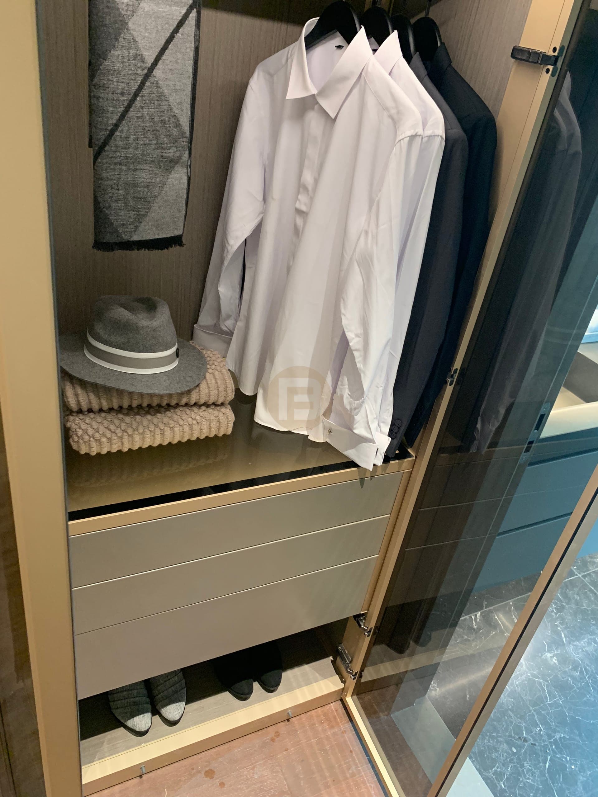 Glass-front fitted wardrobe with bronze-toned frame and internal drawers