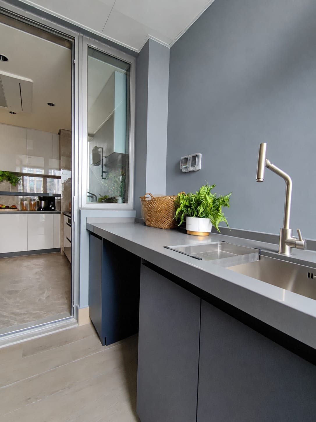 Muebles bajos gris oscuro con encimera y fregadero en el balcón junto a la puerta de cocina