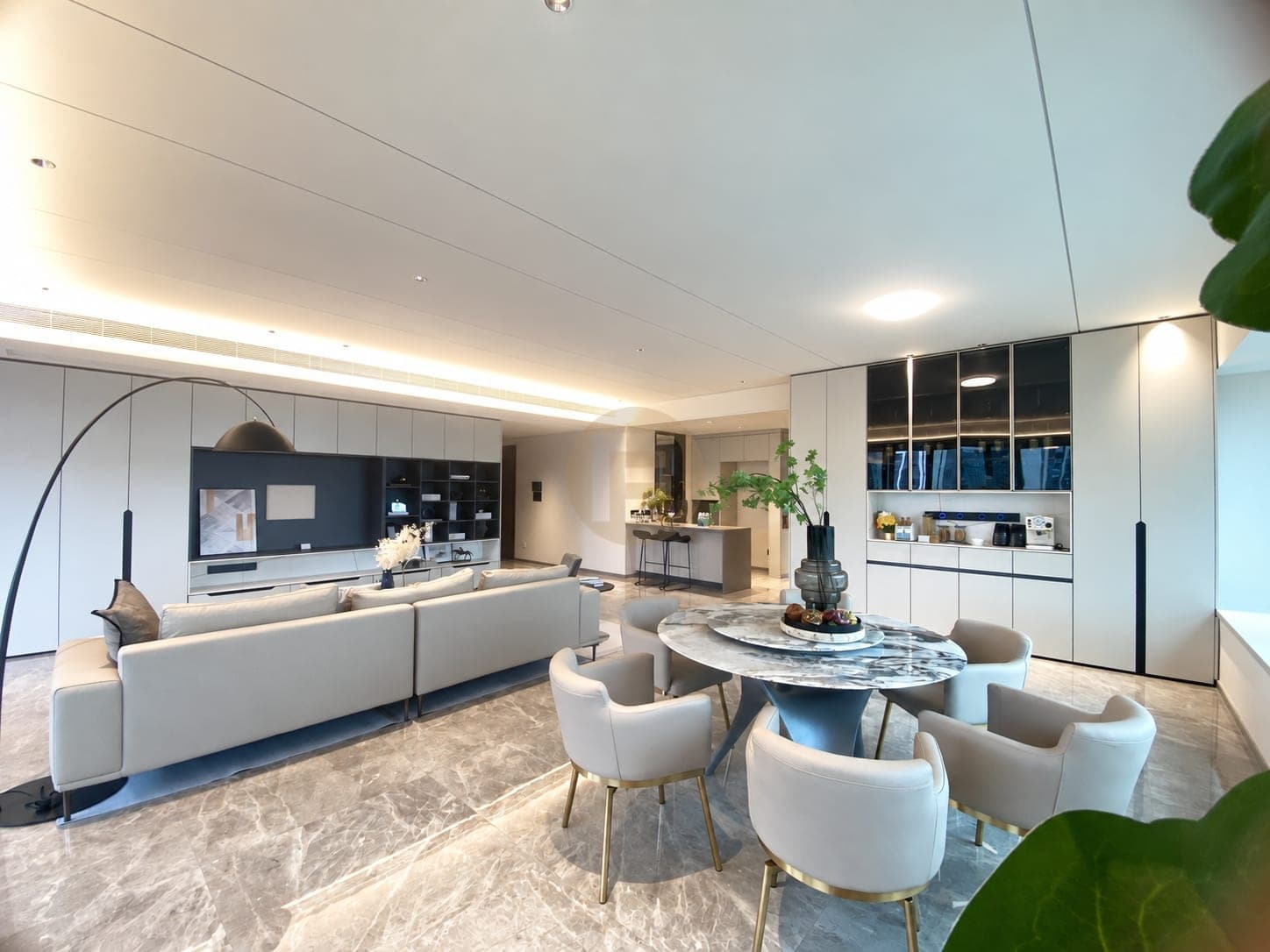 Salón y comedor abiertos con mueble de televisión, vitrina y la isla de cocina al fondo