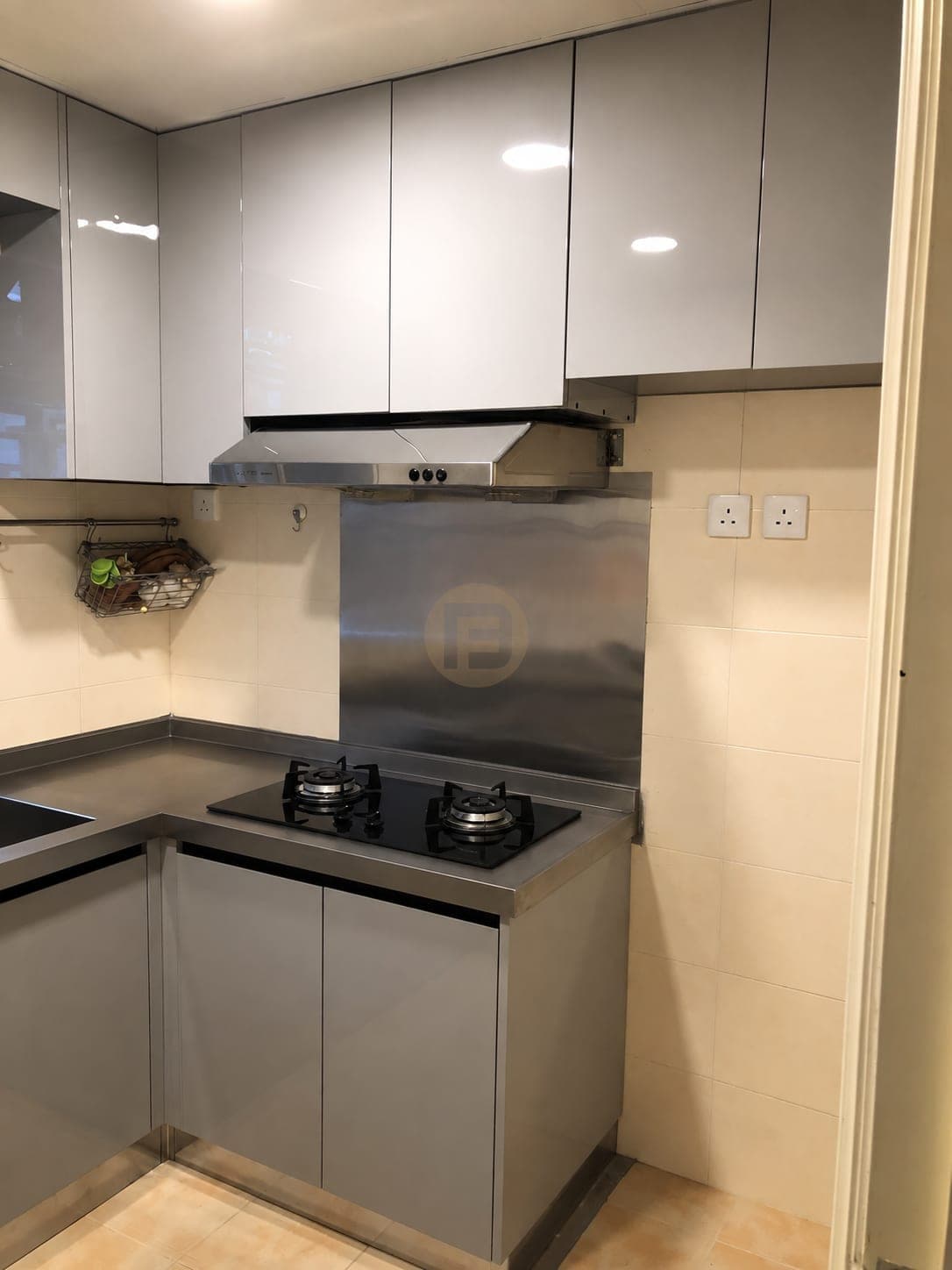 Hob corner with a stainless splashback under grey gloss wall cabinets