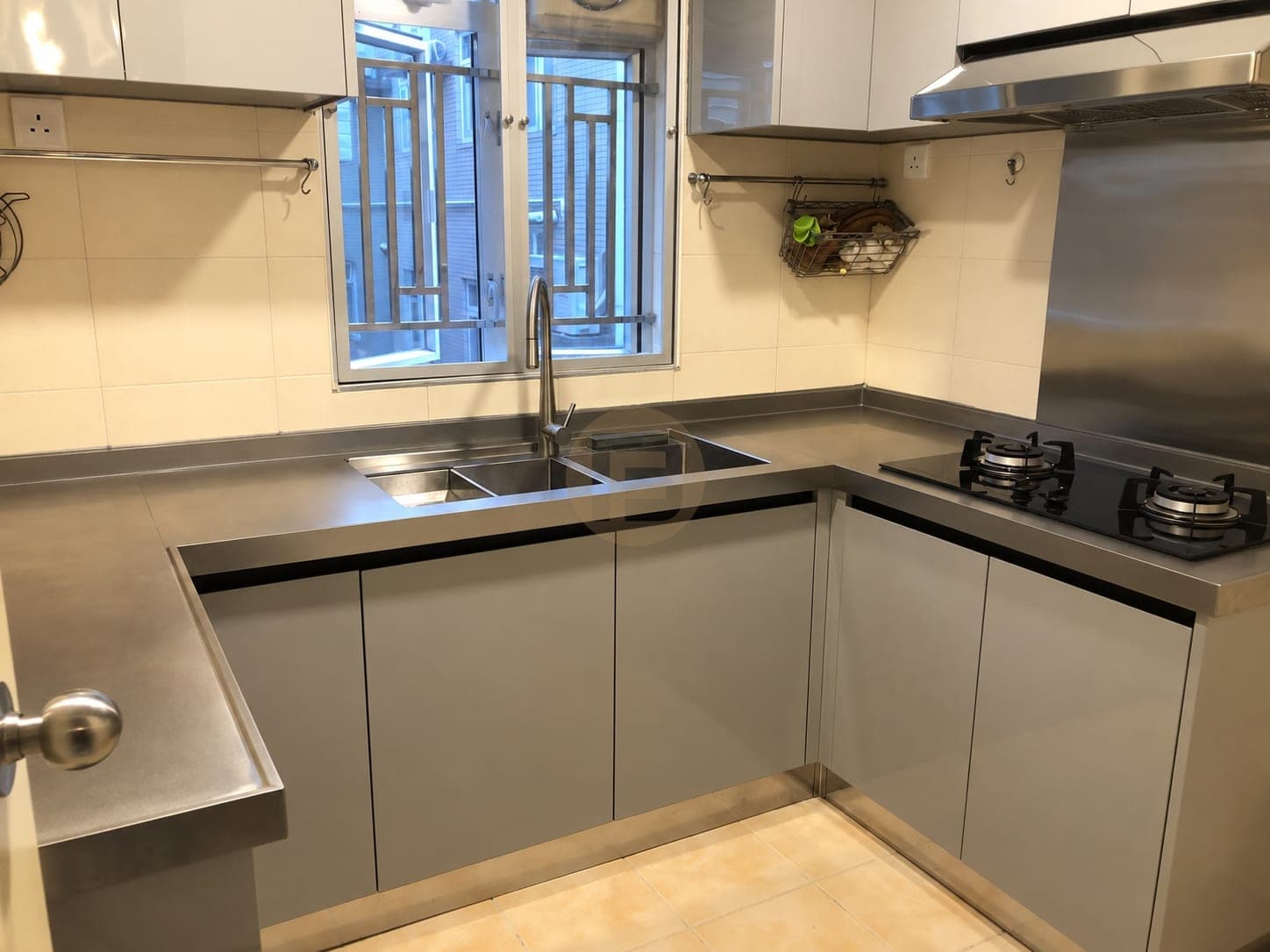 Grey U-shaped kitchen with a stainless steel worktop, window-side double sink and glass hob