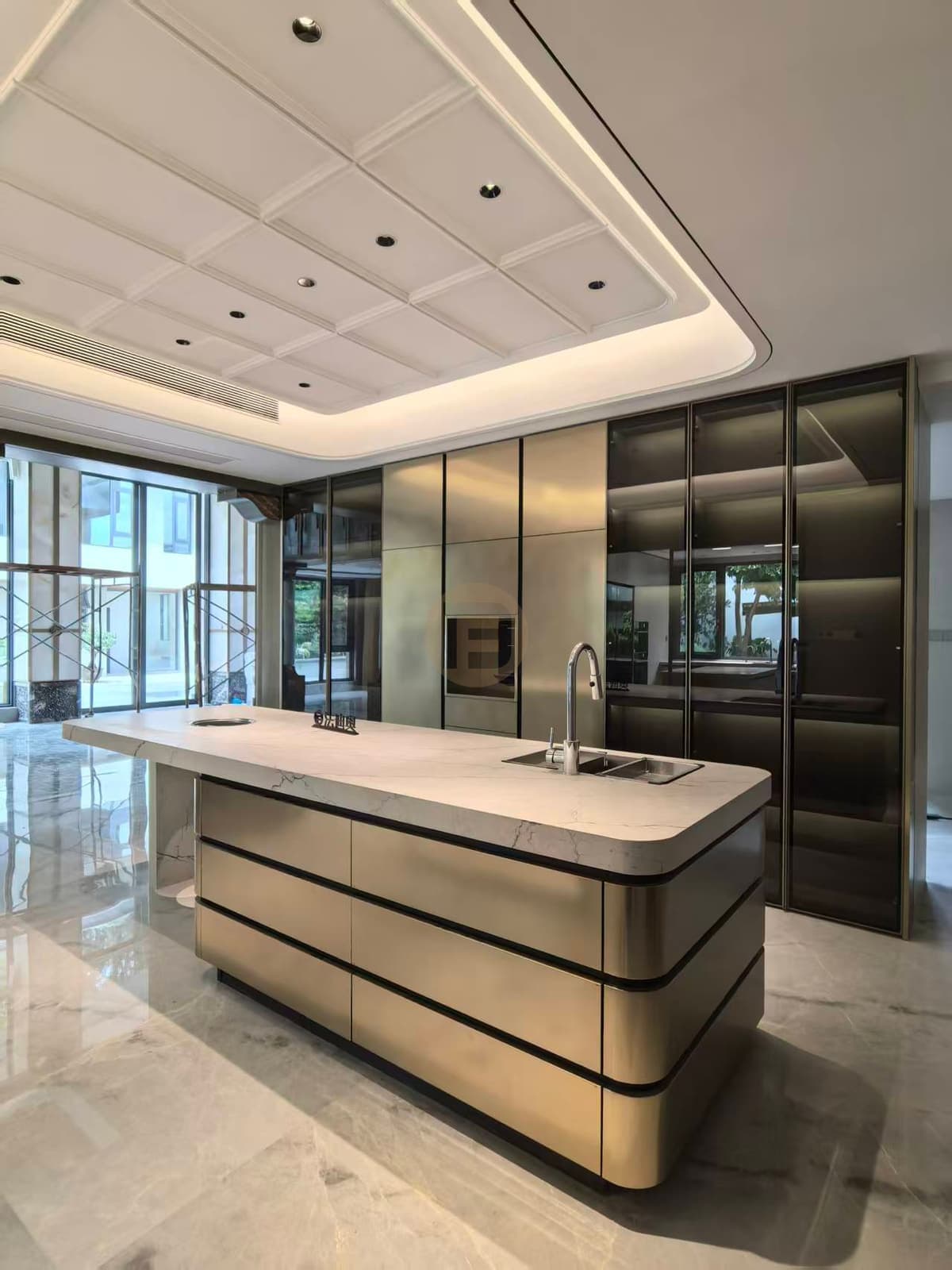 Isla de tono metálico ante pared acristalada y ventana