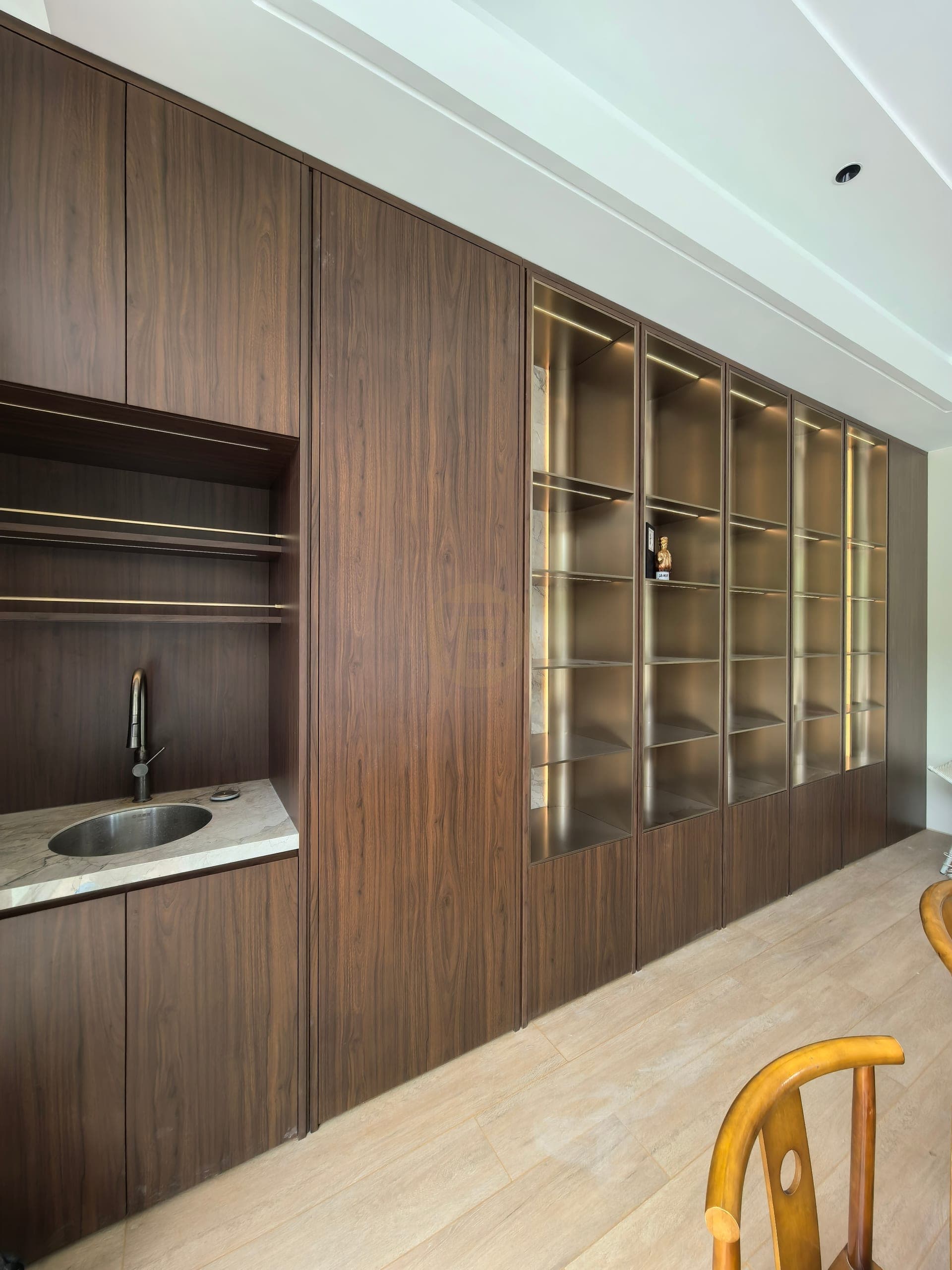 Full view of wood-look display wall with glass cabinets and a nearby sink