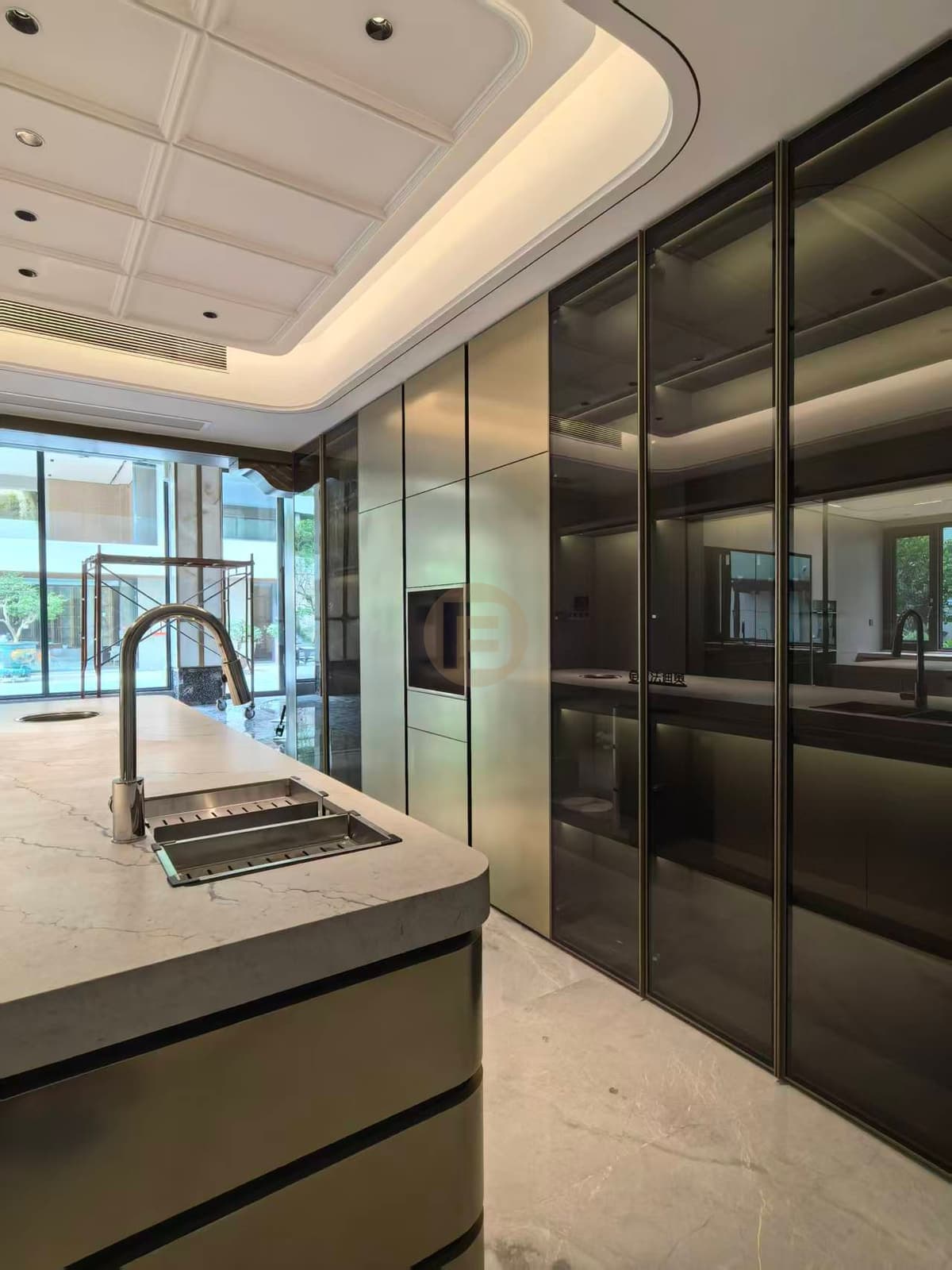 Island sink and glass cabinet wall with scaffolded window beyond
