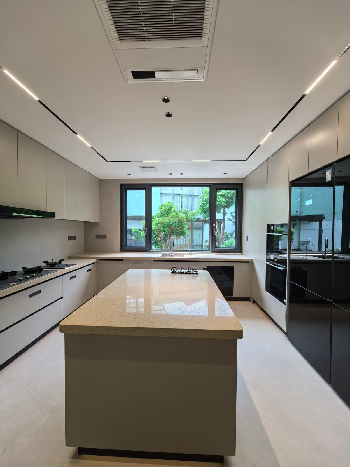 Straight view across light kitchen island to tall cabinetry