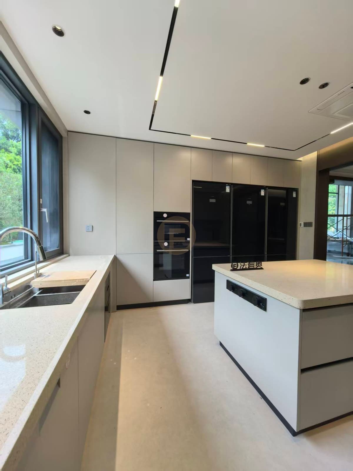 Light kitchen sink below window beside tall cabinet run