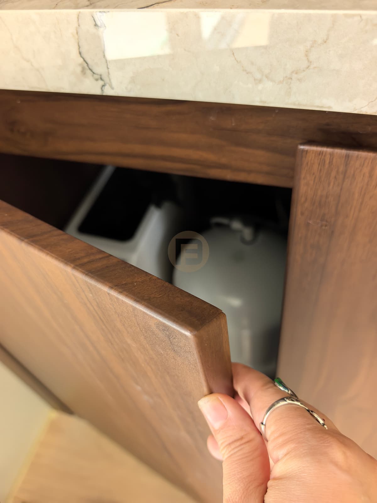 Puerta abierta de mueble de aspecto madera fotografiada con una mano