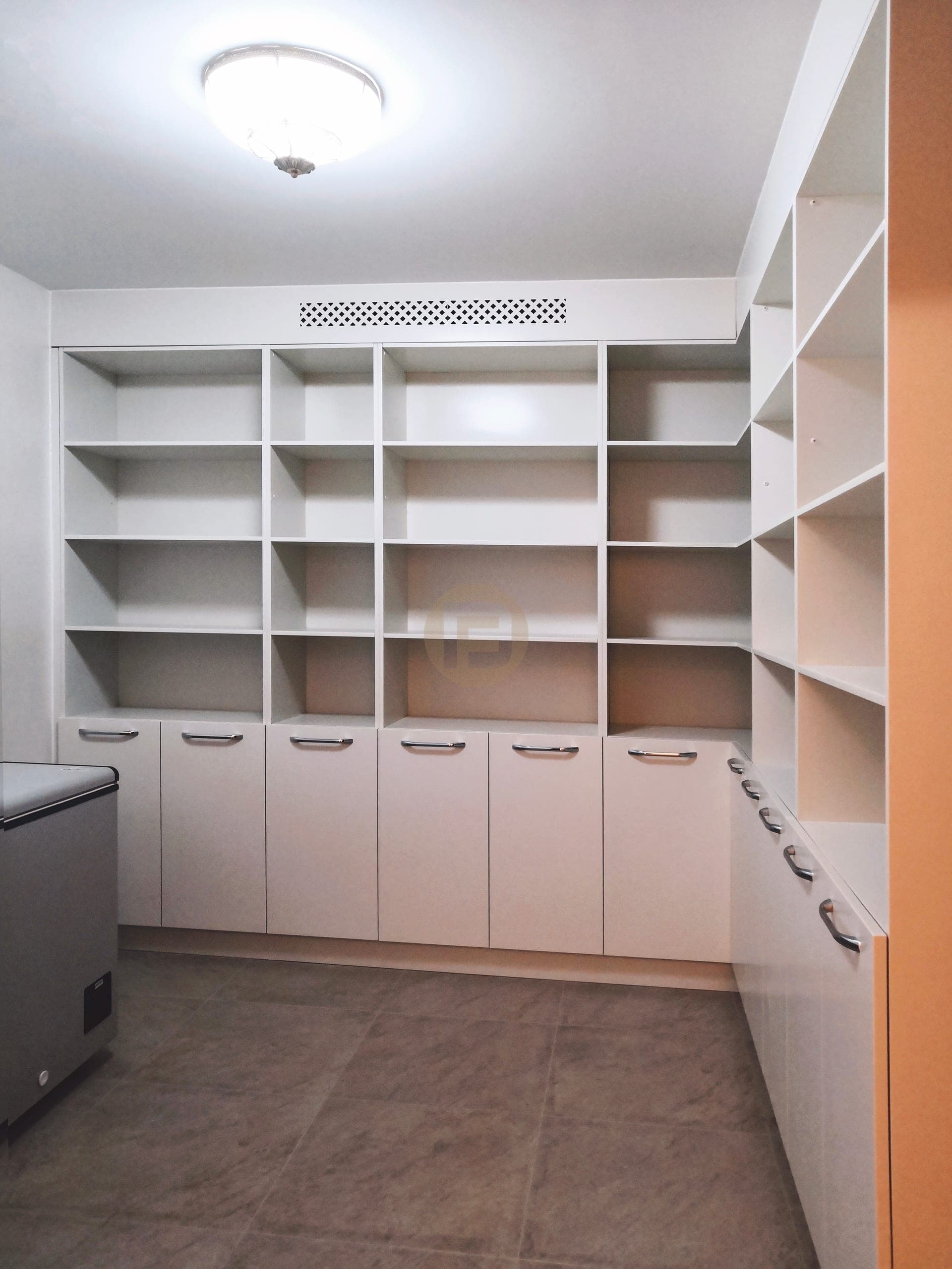 White storage room lined with open shelving above lower cupboards