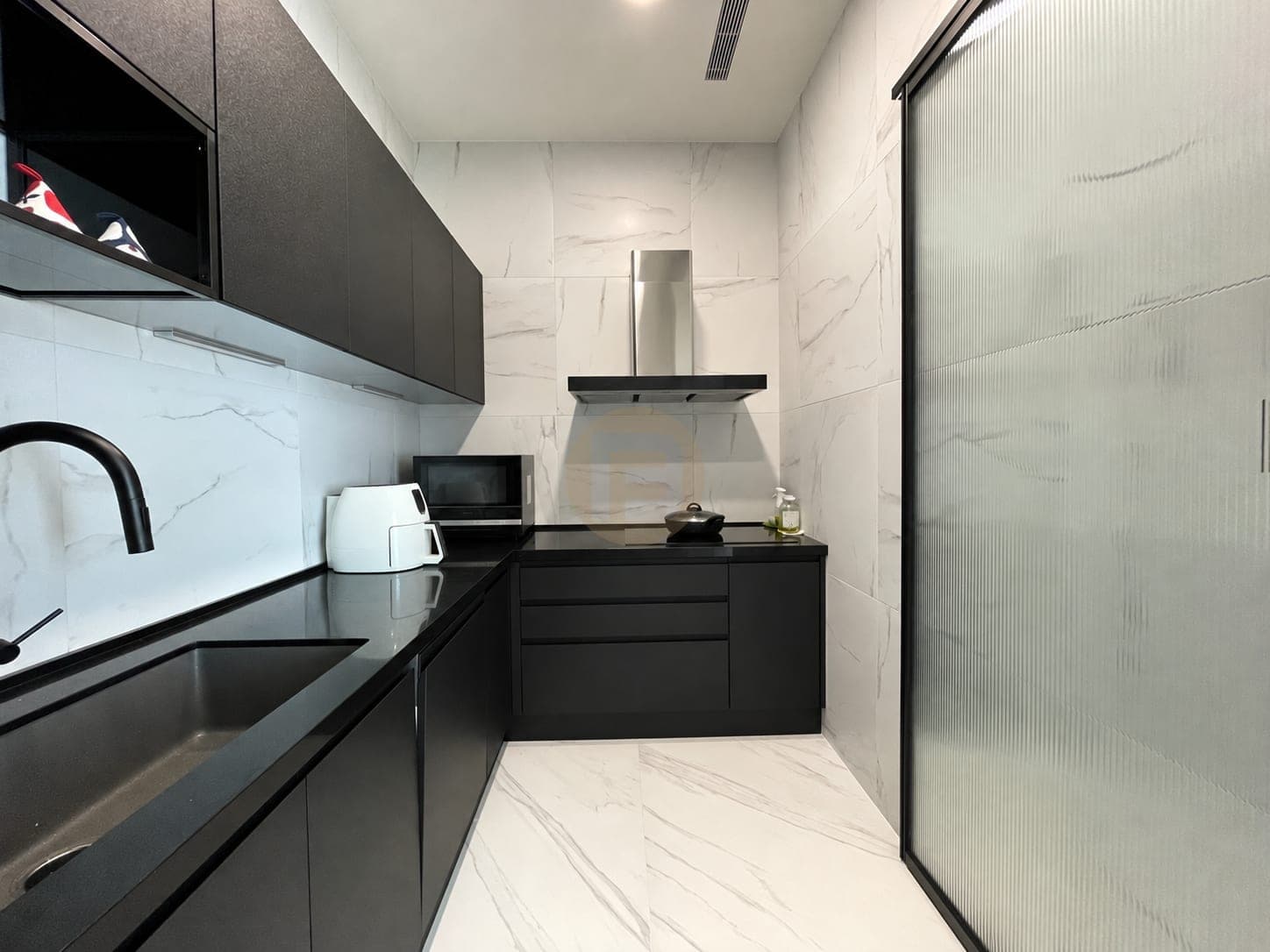 Enclosed dark cooking kitchen behind a fluted-glass door