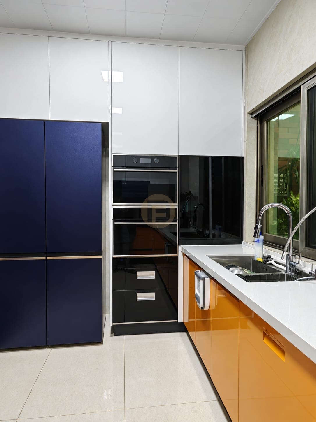 Navy tall cabinets beside a black glass oven column and the orange sink run
