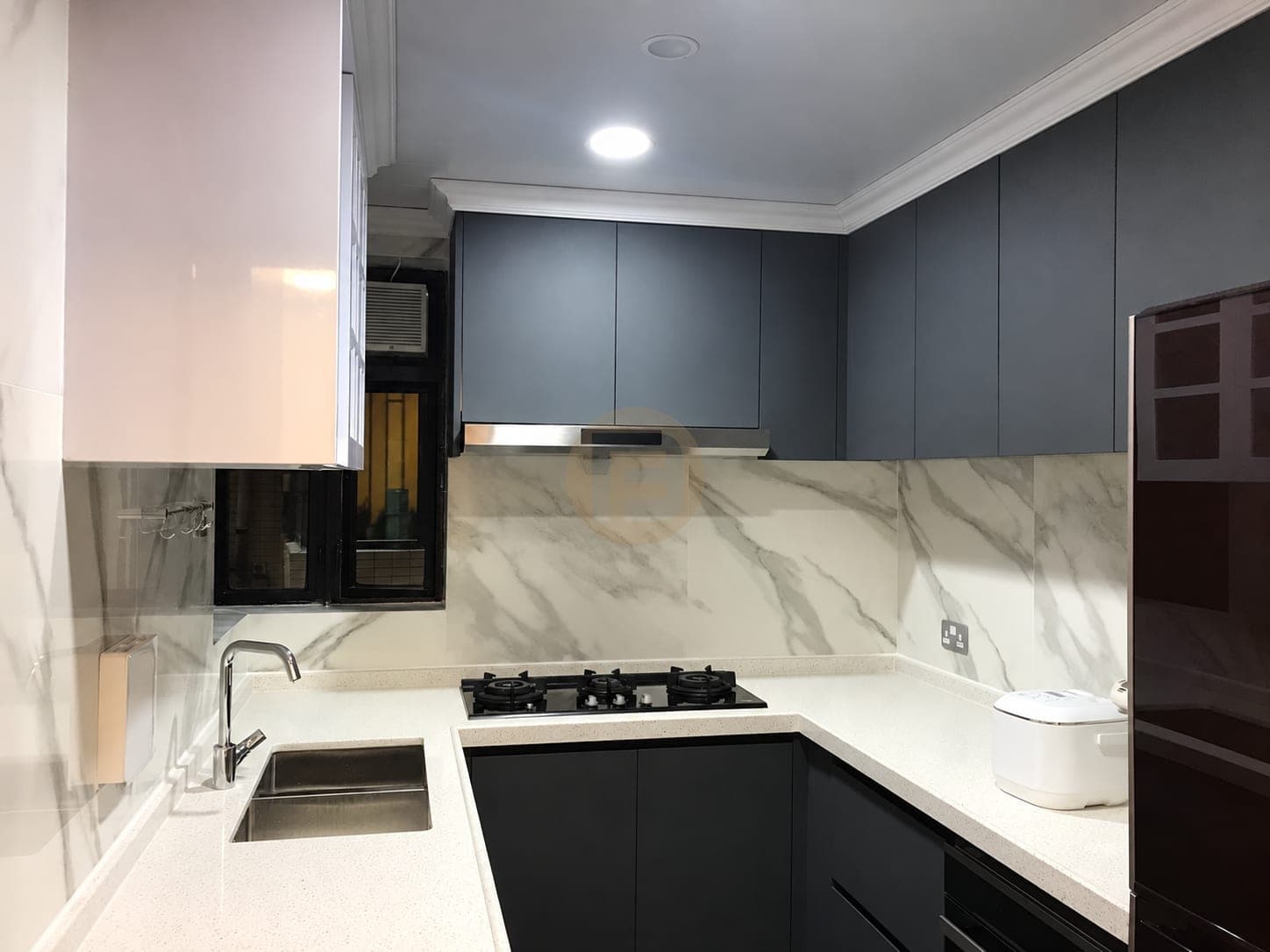 Cocina compacta en U con muebles azul pizarra, encimera blanca y frente de aspecto mármol