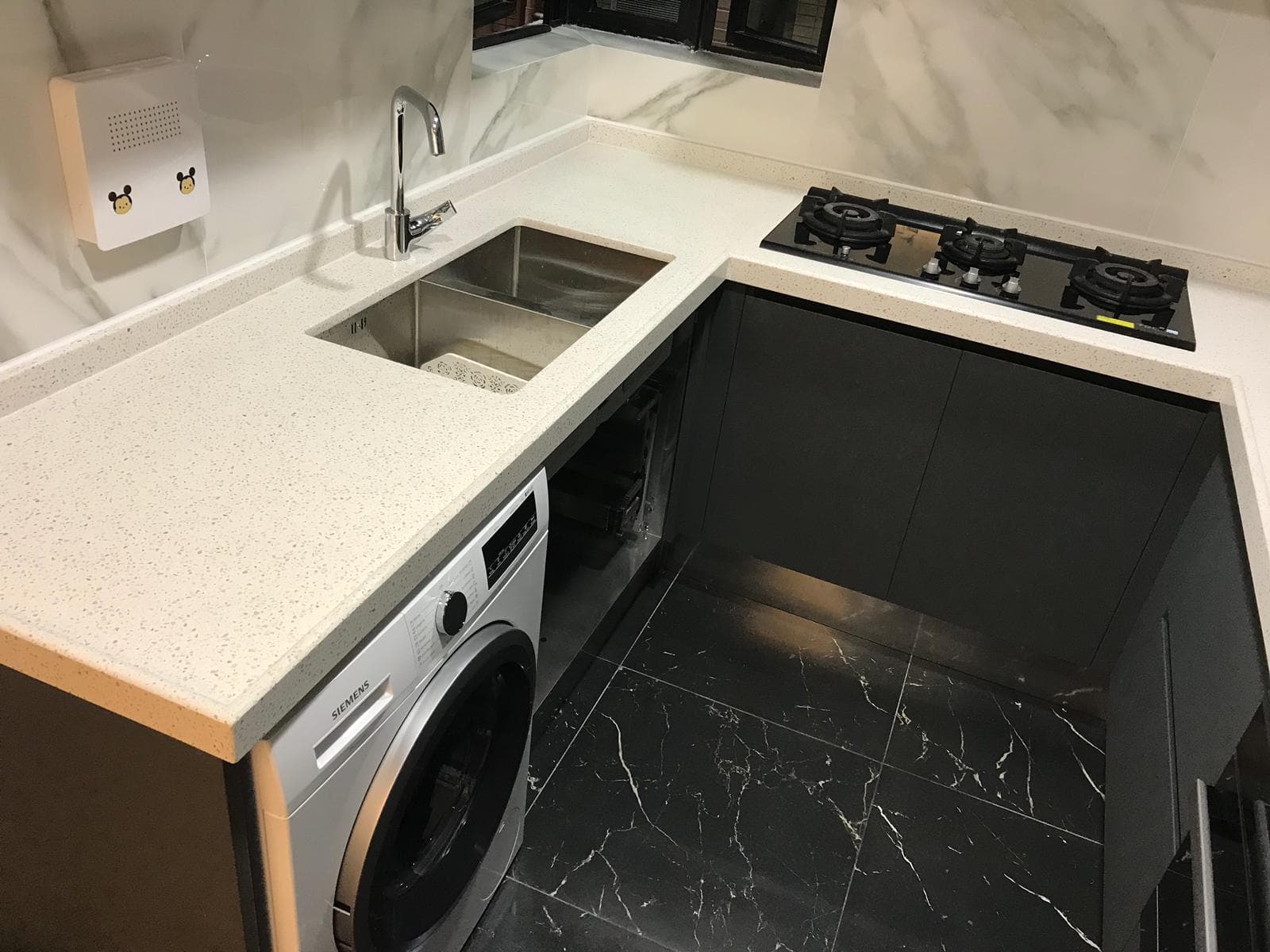 Vista elevada del fregadero, la placa y la lavadora en la cocina compacta oscura