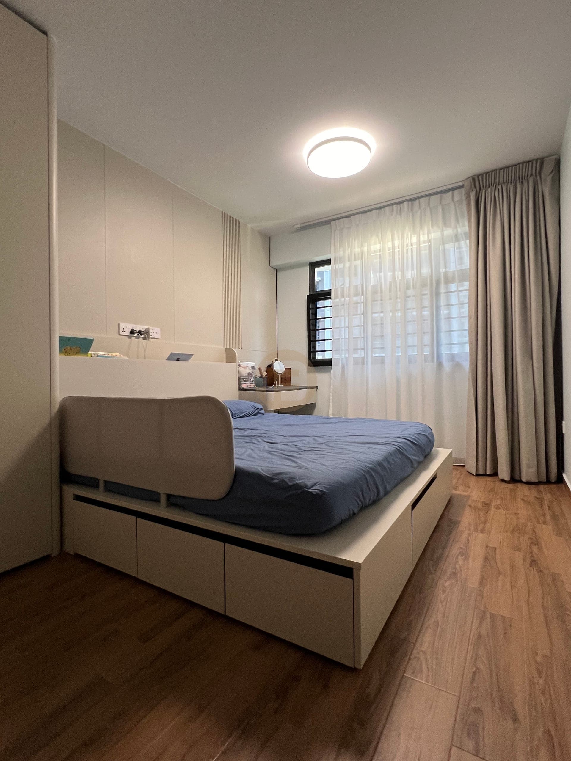 Bedroom storage bed fitted below a curtained window