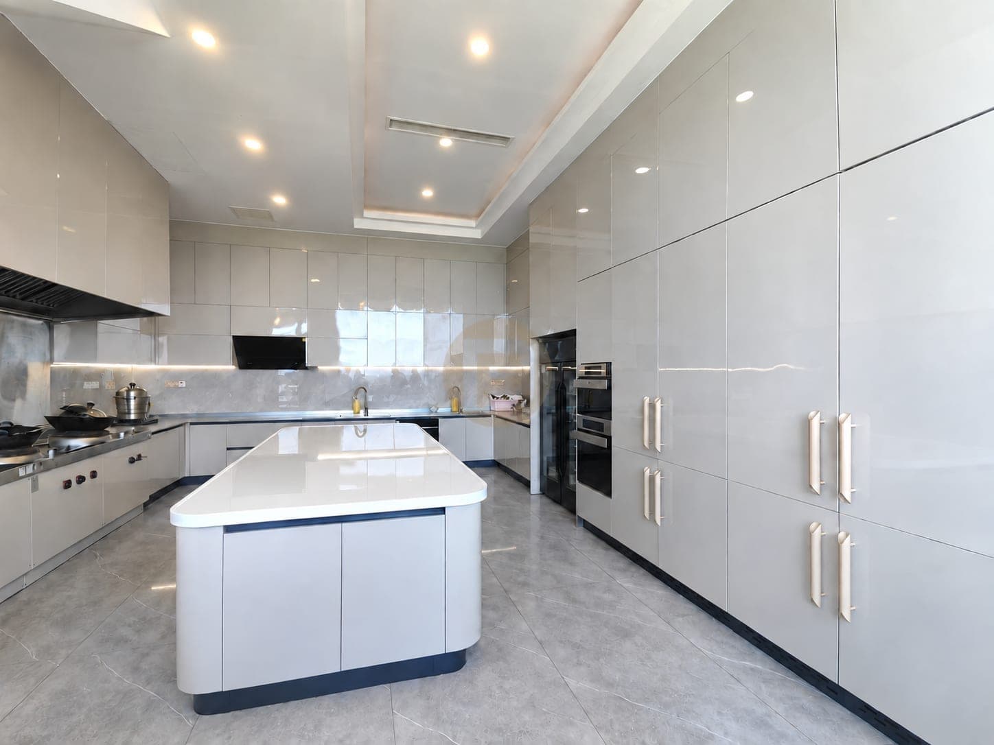 White kitchen with a rounded island and full-height storage wall