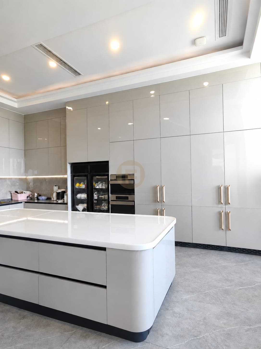 Rounded end of the white island facing the tall cabinet wall