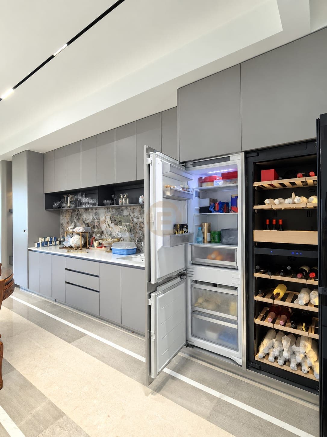 Grey tall-cabinet wall with a built-in fridge, wine cooler and sink run beside the dining area